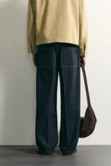 Pantalón jean azul marino oscuro de corte recto y holgado, largo cropped, tiro medio y tejido rígido de denim sin lavado. Cuenta con diseño de cinco bolsillos y costuras en tono tabaco contrastante.