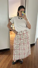 Falda midi blanca con lunares amarillos y bolsillos laterales.