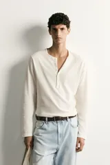 Remera polo de manga larga y calce regular fit en color blanco off-white, confeccionada en mezcla de algodón y lino, con cuello redondo y cartera con botonadura frontal.