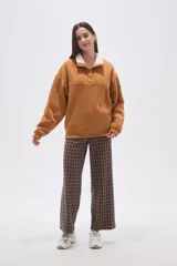 Buzo de algodón color tostado, con cuello polo y cierre frontal parcial con botones. Presenta un detalle de forro de corderito sintético blanco en el cuello y mangas largas con diseño holgado.