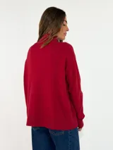 Sweater de punto con cuello alto, manga larga y puños acanalados. Presenta un diseño de corte holgado y tejido suave.