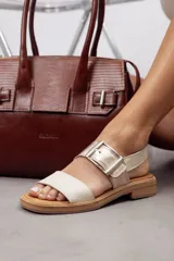 Sandalias de cuero marrón, con diseño de dos fajas amplias, una lisa en la parte delantera y otra superior con hebilla metálica grande y ajustable. Suela plana con plataforma baja y pespunte visible.