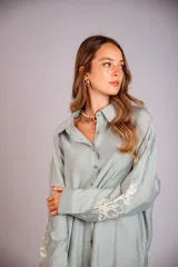 Camisa celeste de corte clásico, con botones frontales y bordados florales en las mangas.