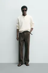 Camiseta relaxed fit color crema, con cuello redondo tipo panadero y cierre frontal de tres botones. Manga larga y acabados en rib.