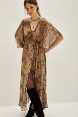 Vestido largo de viscosa con estampado animal print en tonos marrones y negros, escote en V, mangas mariposa y lazo ajustable en la cintura. Presenta una abertura frontal en la falda.