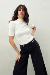 Top de manga corta color blanco, tejido con textura acanalada, cuello alto y terminaciones onduladas en mangas y ruedo.