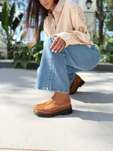 Botas cortas de cuero color marrón con elástico en los laterales y detalle de cuero texturizado en la parte delantera.