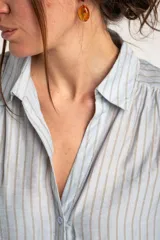 Camisa oversize celeste y beige con rayas verticales, cuello camisero, mangas cortas y cierre frontal con botones.