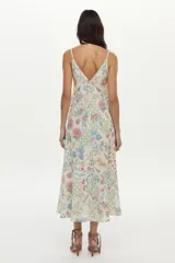 Vestido midi de lino y viscosa color crudo con estampa exclusiva multicolor, escote en V, breteles regulables, bolsillos laterales y detalles de vainillas decorativas.