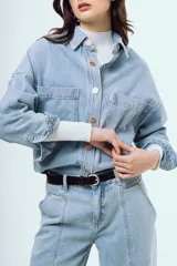 Camisa de denim de corte oversize, color celeste, con bolsillos frontales con solapa y botones metálicos.