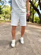 Conjunto deportivo blanco compuesto por una remera de manga corta de corte holgado y un short con cordón ajustable en la cintura.