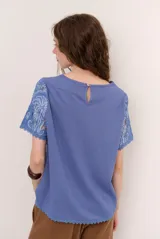 Blusa de encaje con diseño floral y geométrico translúcido, de manga corta y cuello redondo.