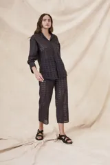 Camisa negra de algodón con bordado calado, corte oversize, cuello clásico, cierre frontal con botones y mangas largas con puños abotonados.