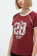 Remera de algodón blanca de manga corta estilo ringer, con cuello y puños en contraste negro. Presenta un estampado frontal con el número '28' relleno de encaje y la inscripción 'San Francisco Sports Club'.
