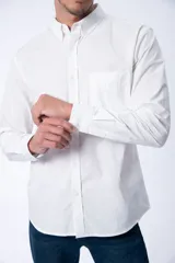 Camisa de vestir manga larga color blanco, con cuello clásico abotonado y bolsillo frontal en el pecho. Diseño de corte recto y puños ajustables con botones.