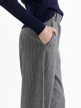 Pantalón de silueta wide leg confeccionado en mezcla de lana, con diseño de rayas verticales y sutiles lentejuelas bordadas. Presenta cierre frontal con gancho y botón interno, bolsillos laterales y bolsillo ojal en la parte posterior.