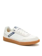 Sneaker Caterpillar modelo Pause Retro, de diseño minimalista con exterior en lona blanca y detalles en gamuza. Presenta suela de goma color caramelo con textura de panal y logo de la marca en el lateral y la lengüeta.