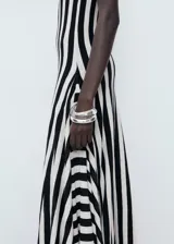 Vestido largo de punto fino con diseño a rayas verticales en blanco y negro, sin mangas, con cuello redondo y corte evasé.