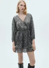 Vestido corto con estampado animal print en tonos grises y negros. Tiene cuello en V cruzado, mangas 3/4 y falda con volantes.