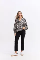Blusa de corte relajado con estampado geométrico en tonos beige y negro. Presenta cuello en V con detalle de frunces, mangas largas abullonadas con puños elásticos y una caída fluida.