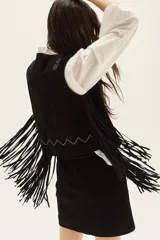 Chaleco de cuero negro con flecos largos en los laterales y detalles bordados en hilo blanco en la espalda.