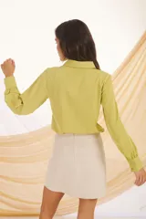 Camisa verde lima de manga larga con puños abullonados y botones dorados.