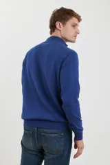 Sweater azul con cuello alto abotonado y dos bolsillos frontales con botón.