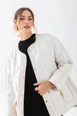 Chaqueta acolchada de color negro con diseño de costuras onduladas. Presenta cuello redondo, cierre frontal con botones a presión y dos bolsillos frontales tipo cargo con solapa y detalle de hebilla. Posee un corte holgado y mangas largas.