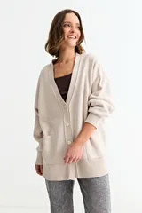 Cardigan de punto color fucsia, con cuello en V, cierre frontal con botones y bolsillos laterales. Presenta un diseño holgado con mangas largas y puños acanalados.