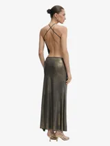 Vestido largo de tejido fino y muy elástico, con acabado metalizado en tonos negro y dorado. Presenta un diseño entallado, escote halter con fruncido y espalda abierta. Incluye un body integrado con cierre de tres corchetes y una abertura lateral alta en la falda.