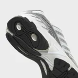 Championes Adidas Adistar Control 3 de color blanco y plateado con diseño inspirado en los años 2000, confeccionados con exterior de malla transpirable y rayas sintéticas.
