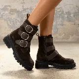 Bota corta de gamuza color marrón oscuro, con suela track negra y tres tiras horizontales con hebillas metálicas plateadas. Cuenta con cierre lateral interno.