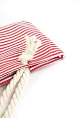 Bolso tipo tote de playa, con diseño de rayas horizontales en color gris y base blanca. Cuenta con asas de soga gruesa en color crudo con nudos decorativos.
