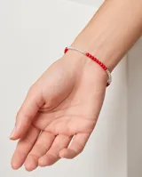 Pulsera elástica compuesta por una combinación de pequeñas perlas blancas, esferas de plata y cuentas de cristal rojo. Diseño delicado y minimalista.
