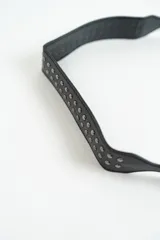 Cartera negra de hombro con diseño de tachas metálicas en la solapa y el cuerpo. Tiene una correa ajustable y un cierre de hebilla decorativo en el frente.