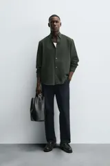 Camisa de corte regular fit confeccionada en tejido de algodón con textura de cuadrillé. Presenta cuello solapa, manga larga con puños abotonados y cierre frontal mediante botonadura.