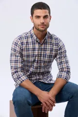 Camisa de manga larga con cuello abotonado y cierre frontal con botones. Presenta un diseño de estampado a cuadros en tonos azul, blanco y naranja.