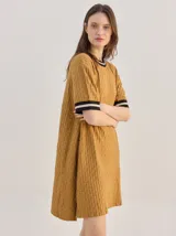 Vestido corto de algodón con estampa geométrica en tonos verde y amarillo, cuello redondo y mangas cortas con puños en color contrastante.
