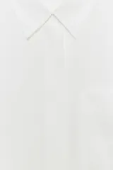 Camisa de corte fluido confeccionada en mezcla de modal, con cuello solapa, manga corta y bolsillo de plastrón en el delantero. Presenta cierre frontal con botones ocultos por tapeta y bajo con aberturas laterales.