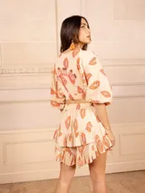 Conjunto de dos piezas compuesto por un top corto de mangas abullonadas con elástico y una falda corta con volados, ambos confeccionados en tela estampada a rayas multicolores.