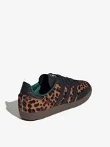Championes Adidas Samba OG con estampado de guepardo, detalles en cuero negro, forro interior verde y suela marrón. Zapatilla de corte bajo con cordones negros y las tres tiras características de Adidas en cuero negro.