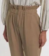 Pantalón carrot color beige confeccionado en viscosa, con cierre delantero en cremallera y cintura elástica.