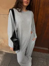 Conjunto de dos piezas color gris melange, confeccionado en tela de lanilla, compuesto por un buzo de manga larga con diseño cruzado al frente y un pantalón largo de corte holgado y tiro alto.