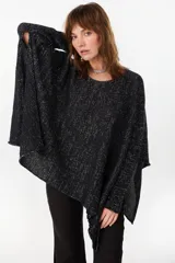 Poncho oversize de punto negro con hilos de lurex plateados, cuello redondo y tajos en los laterales.