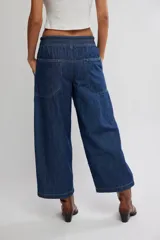 Jean azul de tiro medio con cintura elástica ajustable mediante cordón, bolsillos plaqué delanteros y diseño de pernera ancha y holgada.