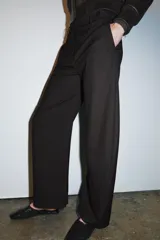 Pantalón de tiro medio con diseño de raya diplomática, confeccionado con cintura con trabillas, bolsillos laterales y cierre frontal con cremallera y botón.