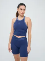 Top deportivo Umbro modelo Kia, color azul marino con detalles en gris en el cuello y sisas. Cuenta con logo estampado en el pecho y diseño de espalda deportiva.