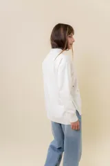 Sweater de tejido de punto color marrón, con cuello alto, corte relajado y terminaciones en rib en puños y cintura. Presenta una hilera de botones metálicos decorativos en uno de los laterales.