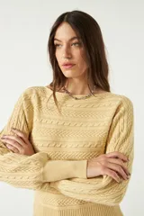 Sweater color amarillo claro, tejido en punto trenzado con cuello redondo y mangas largas abullonadas.