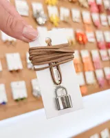 Choker con tiento de gamuza sintética color marrón y dije de candado plateado.